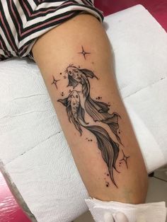 a woman's leg with a tattoo of a fish and stars on the side