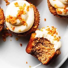 several cupcakes with white frosting and orange sprinkles on a plate