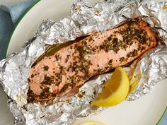 a piece of salmon on tin foil with lemon wedges and seasoning next to it