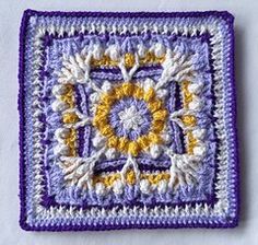 a crocheted square with yellow and white flowers in the center on a white surface