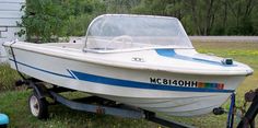 a white and blue boat sitting on top of a grass covered field next to a building