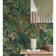 the wallpaper in this room is painted with tropical leaves and has a mirror above it