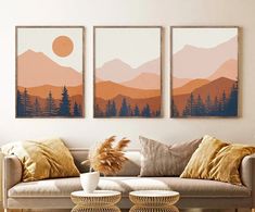 three paintings on the wall above a couch in a living room with pillows and coffee table