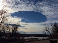 a large object is in the sky above some trees and water, with a fence around it