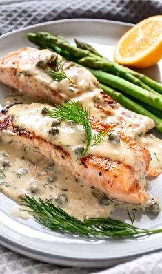 grilled salmon fillets with cream sauce and asparagus on a white plate