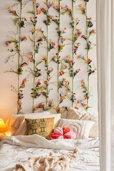 a bed with flowers on the wall behind it and a lamp in front of it