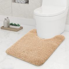 a white toilet sitting next to a beige rug on top of a bathroom floor in front of a sink