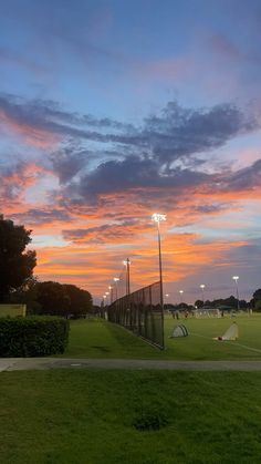 the sun is setting over a soccer field