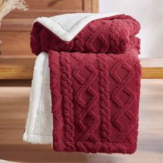 a red and white blanket sitting on top of a wooden floor