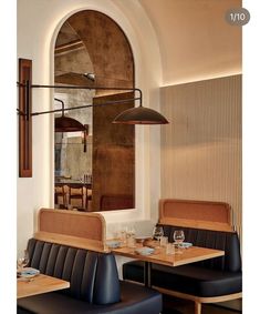 an empty restaurant with black leather booths and wooden tables in front of a large arched window