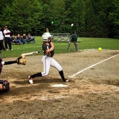 a baseball player swinging at a ball during a game with other players in the background