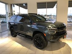 a grey suv is parked in a showroom with large windows and tile flooring