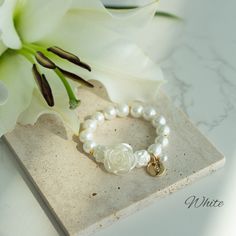 Charming Customizable Flower Girl Bracelet with Pearl Rose Centerpiece Make your flower girl feel extra special with this enchanting bracelet, thoughtfully designed to add a touch of elegance and personal charm to her ensemble. At the heart of this exquisite piece sits a large, light pink rose bead, symbolizing the blooming love and joy of your special day. This central rose is flanked by a strand of lustrous glass pearls, each one carefully selected for its soft glow and flawless finish, mirror Elegant Beaded Bracelets With Flower Charm And Round Beads, Flower-shaped Stretch Bracelet As Gift, Flower Shaped Stretch Bracelet For Gift, Flower Shaped Stretch Bracelet As Gift, White Flower Charm Bracelet For Wedding, White Wedding Bracelets With Flower Charm, White Wedding Bracelet With Flower Charm, Adjustable Pearl White Flower-shaped Jewelry, Adjustable Pearl Bracelet With Flower Shape