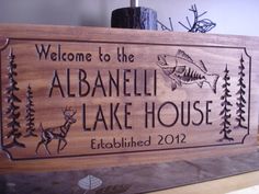 the welcome sign to the lake house is made out of wood and has an image of a fish on it