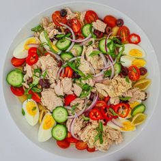 a white bowl filled with lots of different types of food on top of a table