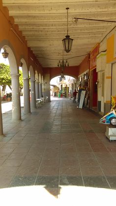 an empty walkway with benches and lamps on either side