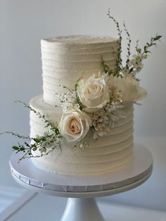 a white wedding cake with flowers and greenery