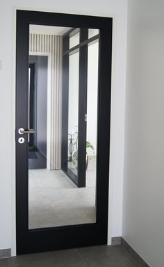 a black door with a mirror on the side of it in front of a white wall