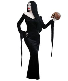 a woman dressed in black holding a skull and wearing a long dress with an elaborate headpiece