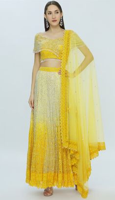 Yellow lehenga with all-over embroidery, paired with asymmetric layered blouse and dupatta, featuring a v-neckline, short sleeves, tassel detail on blouse and sleeves, and a cutout lace border on the dupatta. Chikankari Suits, Embroidered Lehenga, Layered Blouse, Embroidered Neckline