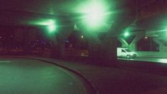 an empty parking lot at night with green lights