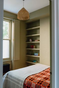 a bedroom with a bed, bookcases and a lamp hanging from the ceiling