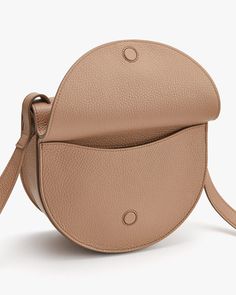 A modern interpretation of the classic saddle bag, made in luxurious Italian leather as the perfect partner for your off-duty outings. Chic Beige Saddle Bag, Modern Beige Saddle Bag For Travel, Modern Beige Saddle Bag With Adjustable Strap, Chic Beige Saddle Bag For Office, Modern Beige Saddle Bag, Top Handle Saddle Bag With Smooth Grain, Modern Textured Leather Saddle Bag For Travel, Chic Saddle Bag For Daily Use, Chic Saddle Satchel For Travel