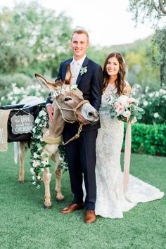 a bride and groom standing next to a donkey with flowers in it's bridle