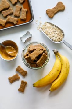 dog treats and peanut butter are on the table next to bananas, oatmeal, and cookie cutters