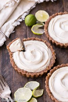 three small pies with white frosting and limes on the side next to each other