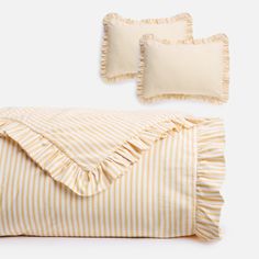 the yellow and white striped bedding has ruffles at the bottom, along with two pillows