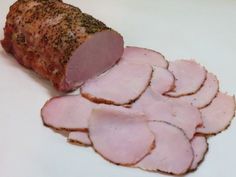 slices of ham on a white plate with seasoning sprinkled around it and sliced into small pieces