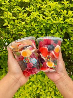 two people holding up plastic cups filled with candy