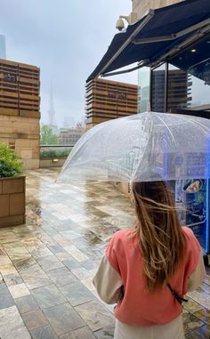 a woman holding an umbrella while walking down a sidewalk