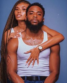 a man and woman standing next to each other in front of a blue background with one holding his arm around the other's shoulder