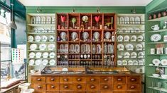 a room filled with lots of plates and vases on top of wooden shelves next to each other