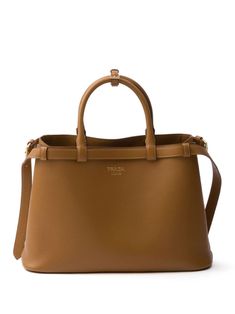 caramel brown leather smoothing finish belted silhouette logo stamp to the front two rolled top handles adjustable handle wrap two adjustable detachable shoulder straps open top partitioned compartment multiple internal slip pockets full lining gold-tone hardware rectangle body Silhouette Logo, Patchwork Tote Bags, Large Leather Tote Bag, Buckle Bags, Patent Leather Loafers, Large Leather Tote, Chicago Pd, Caramel Brown, Prada Handbags