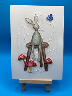 a card with an image of a rabbit sitting on mushrooms