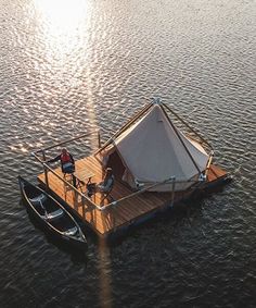 a small boat floating on top of a body of water next to a man standing on it