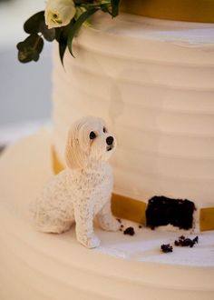 a white dog figurine sitting on top of a cake