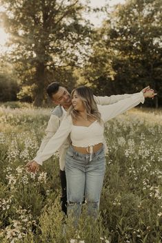 a man and woman are standing in the middle of a field with wildflowers