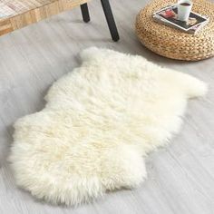 a white sheepskin rug sitting on top of a wooden floor next to a table