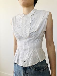 Beautiful Victorian French white cotton camisole with intricate lace details at front. The tailoring at waist line is amazing. There are a row of buttons behind the front leaf panels. There's a signature hidden next to the buttons. Fits a size xs Bust: Waist: Length: Shoulder width: Great vintage condition. No holes Fitted Sleeveless Broderie Anglaise Top, Fitted Classic Tops With Broderie Anglaise, Fitted Broderie Anglaise Top For Daywear, Fitted Vintage White Cotton Top, Fitted Vintage White Top With Lace Trim, Fitted Cotton Top In Vintage White, Sleeveless Cotton Top With Lace Collar, Elegant Vintage White Cotton Tops, Fitted Vintage White Top