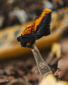 a man with tattoos holding up a glove in front of his face at a soccer game