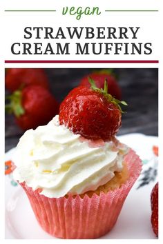 a strawberry cupcake with cream frosting and fresh strawberries on top, sitting on a plate