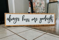 a wooden sign that says, always kiss me goodnight on the floor in front of a door