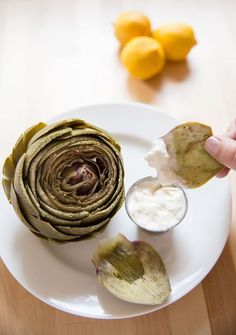 a person is holding up some food on a white plate with lemons in the background