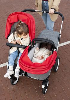 a woman pushing a stroller with two babies in it