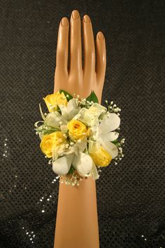 a bouquet of yellow and white flowers on a mannequin's hand with sequins