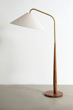 a wooden table lamp with a white shade on it's base and a gold metal arm